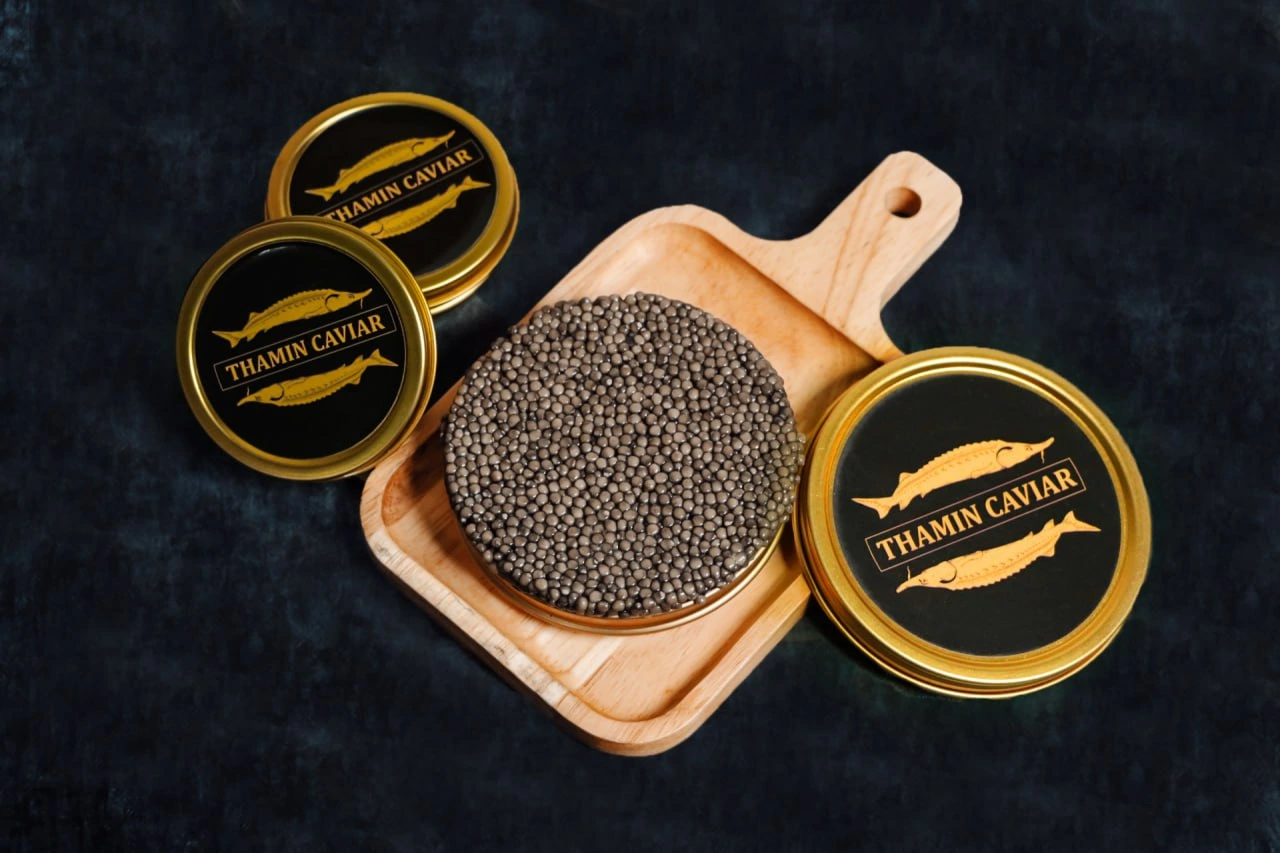 Thamin Caviar tins and open caviar disc on wooden serving board